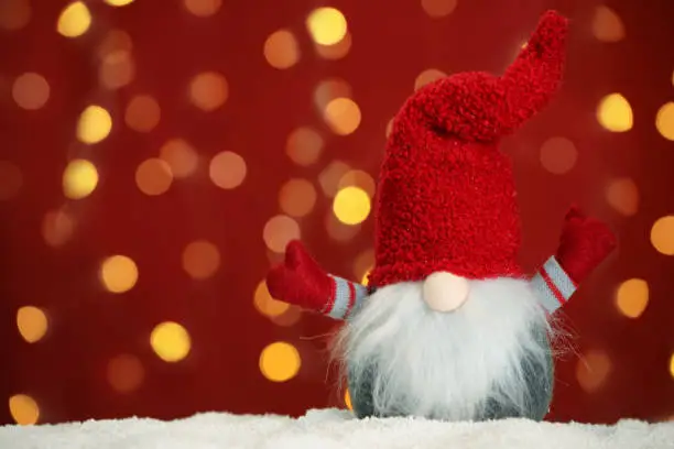 Cute Christmas gnome on snow against blurred festive lights. Space for text