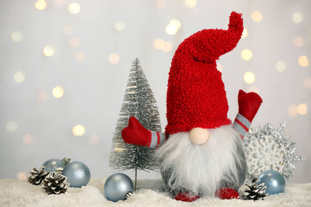 istock Cute Christmas gnome and festive decor on snow against blurred lights 1413038578