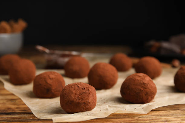 istock Delicious chocolate truffles powdered with cocoa on wooden table, closeup. Space for text 1413038819