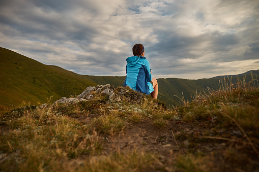 Female tourist sitting and enjoy view of Mountain range. Carpathian Mountain, Ukraine. Walking and hiking trails in Borzhava ridge. Rural area of carpathian mountains in autumn