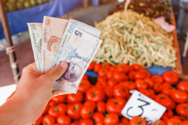 Turkish lira banknotes in hand against the background of vegetables at the farmer's market. The concept of consumer economy and inflation of the national currency of Turkey. stock photo