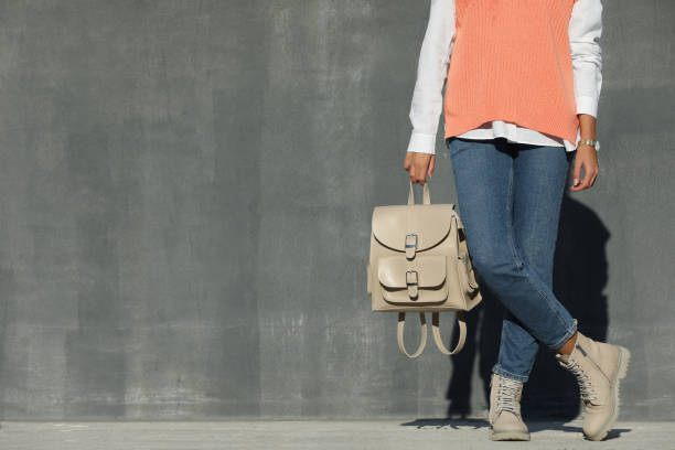 istock Young woman with stylish beige backpack near grey wall outdoors, closeup. Space for text 1413042140