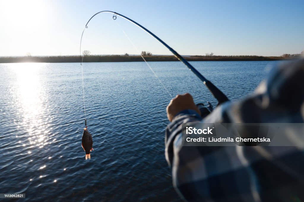 Fisherman catching fish with rod at riverside, closeup Fishing Stock Photo