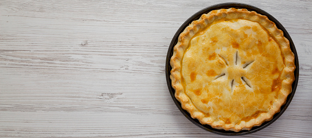 A Piece of Chicken Pot Pie on a white wooden surface, top view. Flat lay, overhead, from above. Space for text.