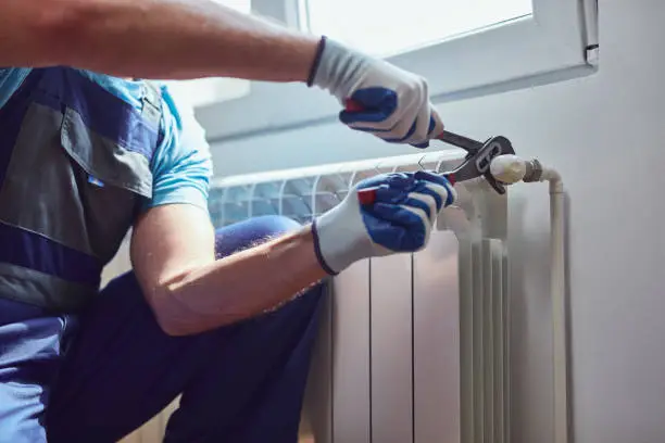 Central heating mechanic and handyman fixing home radiator, gas crisis and seasonal issues.