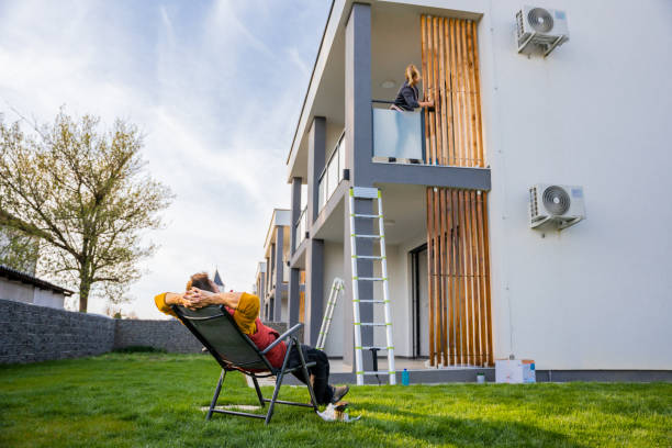 istock Man relaxing on deck chair while woman coloring apartment against sky 1413046987