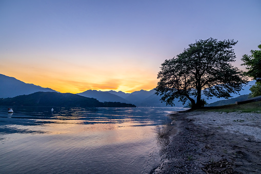 Beautiful view of tranquil Como lake against mountain range and orange sky during sunset