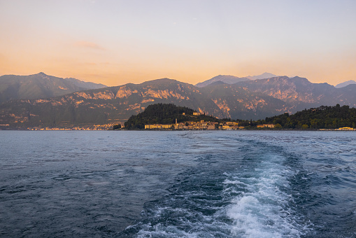 Beautiful view of wake in lake water against mountains and clear sky during sunset