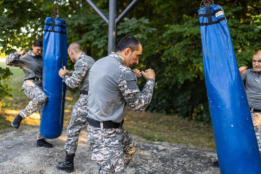 Caucasian female and male military team, having an outdoor military training, while punching the punching bag