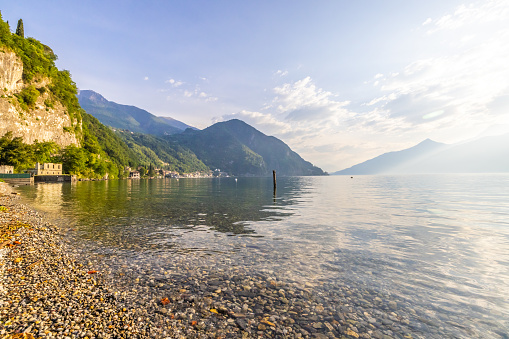 Beautiful view of Como lakeshore by mountains against sky during sunny day