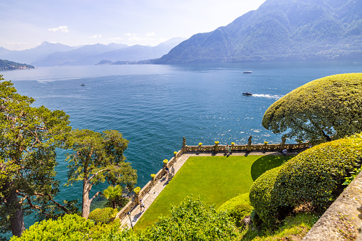 High angle view of trees growing in public park against lake and mountains on sunny day