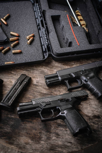 istock Disassembly and cleaning Maintaining a 9mm semi-automatic pistol on a wooden table. 1413052991