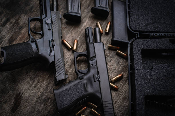 Two 9mm pistols hold slides on a wooden table. Two 9mm pistols hold slides on a wooden table. gun stock pictures, royalty-free photos & images