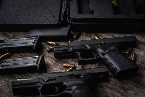 istock Two 9mm pistols hold slides on a wooden table. 1413053049