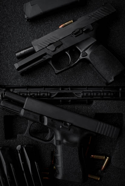 istock Two 9mm pistols hold slides on a wooden table. 1413053055