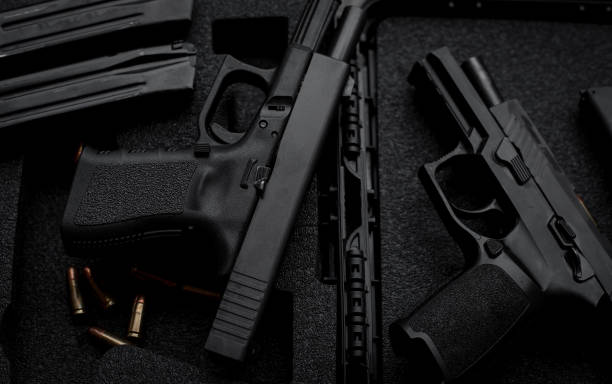 istock Two 9mm pistols hold slides on a wooden table. 1413053080