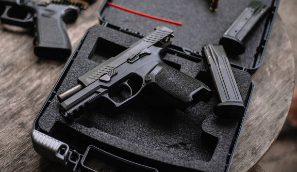 istock Disassembly and cleaning Maintaining a 9mm semi-automatic pistol on a wooden table. 1413053087