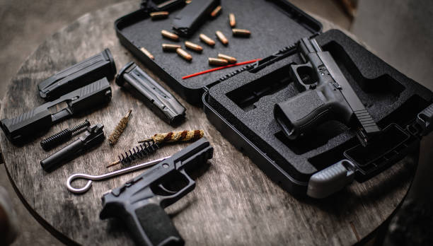 istock Disassembly and cleaning Maintaining a 9mm semi-automatic pistol on a wooden table. 1413053185