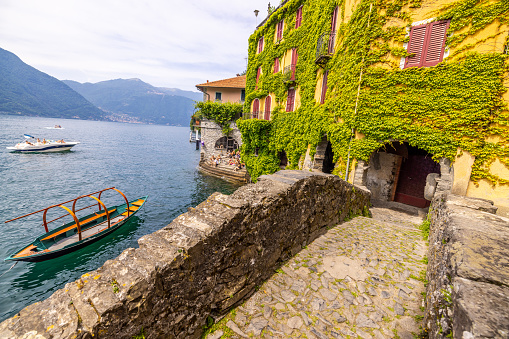 High angle view of walkway leading towards creeper covered old house by nautical vessel on lake