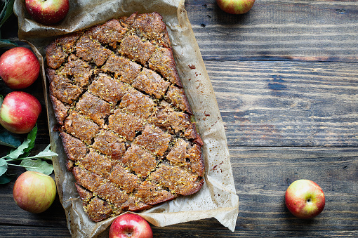 Gluten free apple and walnut cake with sweet syrup topping. Made with almond flour perfect for Passover, Rosh Hashanah or an autumn dessert. Table top view over rustic wood background.
