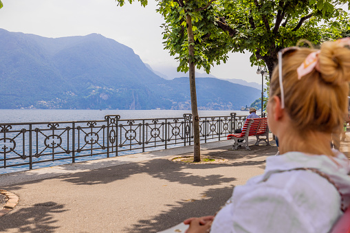 Woman looking at lake and mountains while sitting on park bench in old town