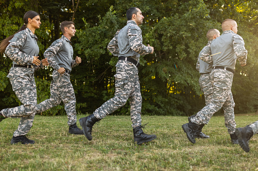 Group of Caucasian female and male people, having an outdoor military training, while running