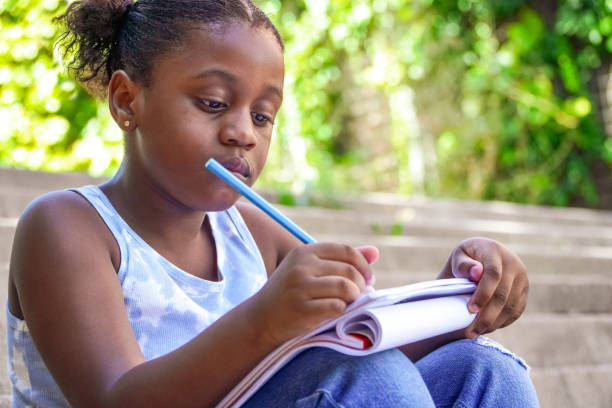 Elementary school girl doing homework at school entrance stairs. copy space
