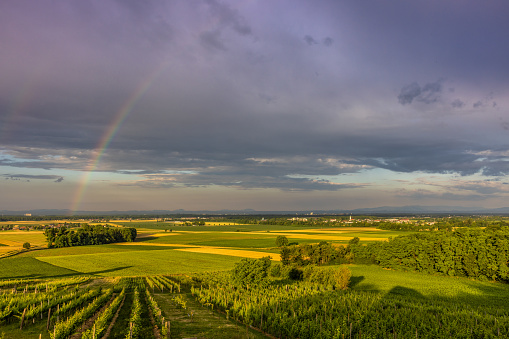 Scenic view of rainbow in storm clouds over beautiful green rural landscape