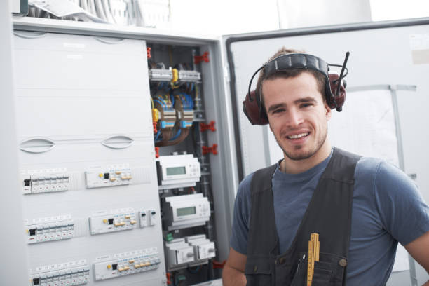 empreiteiro e engenheiro fixando uma placa de distribuição de circuitos elétricos para um projeto de arquitetura industrial em um canteiro de obras. retrato de um eletricista feliz fazendo manutenção em uma máquina - home addition audio - fotografias e filmes do acervo