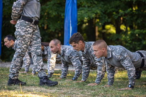 Group of Caucasian female and male people, having an outdoor military training, leaded by female sergeant