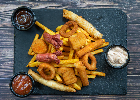 Fresh fried french fries with ketchup and white sauce on wooden background