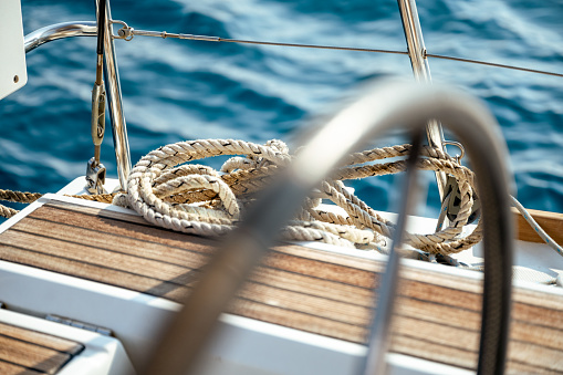 A rope on a wooden part of a sailboat and a sea in the background.