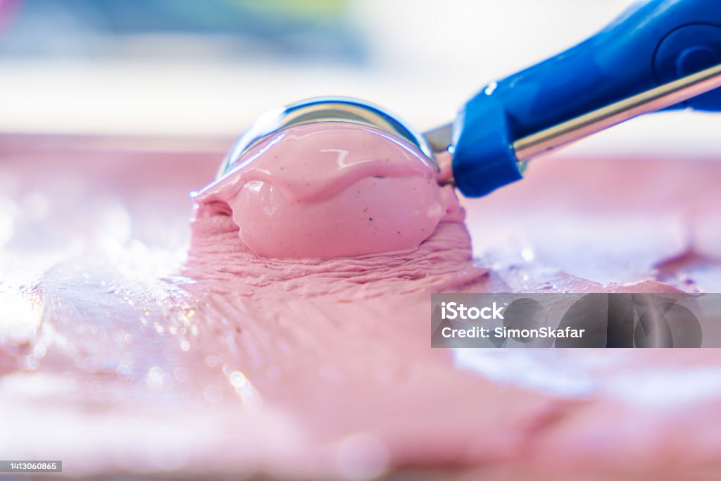 Strawberry ice cream with scoop in freezer Strawberry ice cream with blue scoop in display freezer Ice Cream Stock Photo