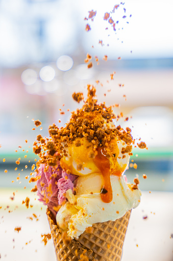 Stack of colorful ice cream scoops sprinkled with crumbs in waffle cone