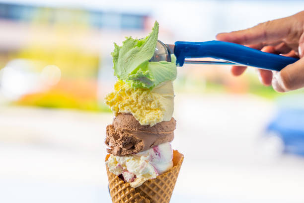 Man serving different colors ice cream scoops in cone