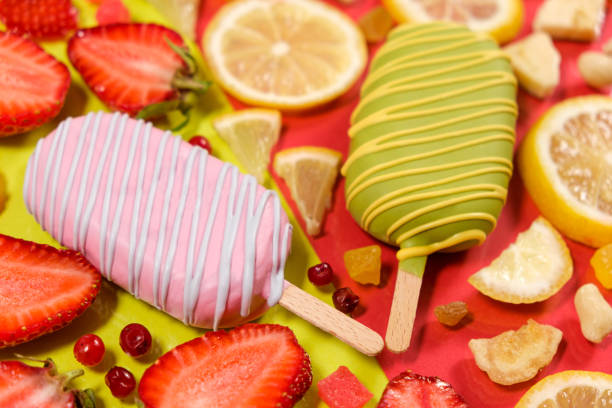 Two ice creams on a sticks - strawberry and lemon on a yellow and red background. Summer fruit desserts.