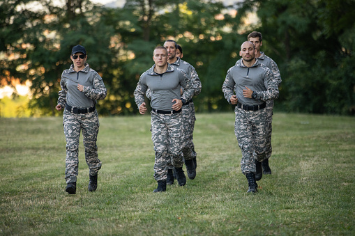 Group of Caucasian female and male people, having an outdoor military training, while running