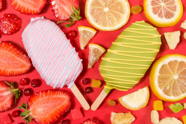 Two ice creams on a sticks - strawberry and lemon on a red background. Summer fruit desserts.