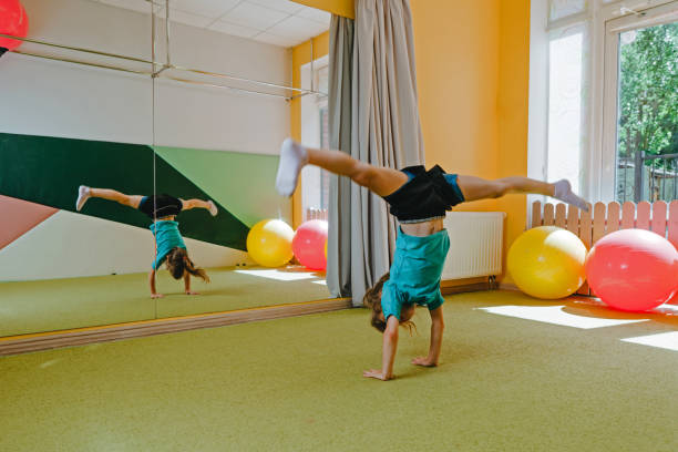 Little girl doing handstand with twine in sport gym Little girl doing handstand with twine in sport gym. Preschooler doing acrobatic cartwheel on the mat. Health concept. acrobatic gymnastics stock pictures, royalty-free photos & images