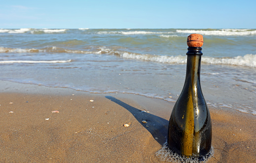beached bottle with cork with a secret message inside by the sea