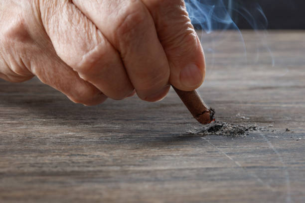istock Elderly human hand puts out a cigar on the table. 1413062328