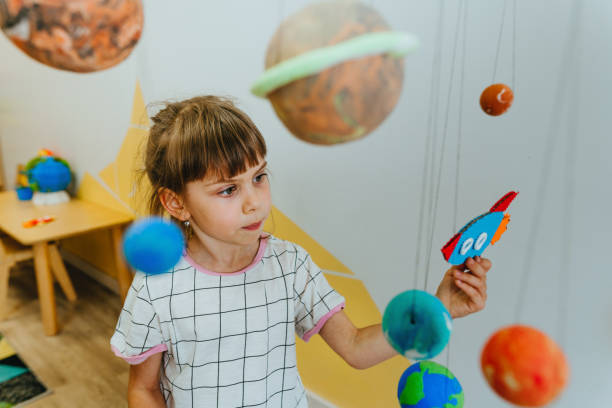 istock Little girl playing with paper spaceship learning Solar system planets 1413062452