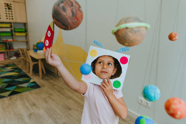 istock Little girl playing with paper spaceship learning Solar system planets 1413062516