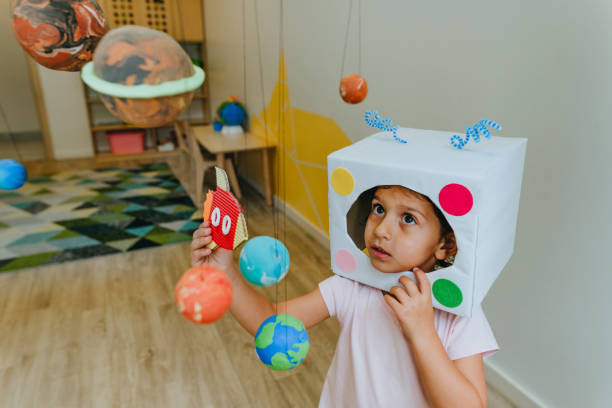 istock Little girl playing with paper spaceship learning Solar system planets 1413062581