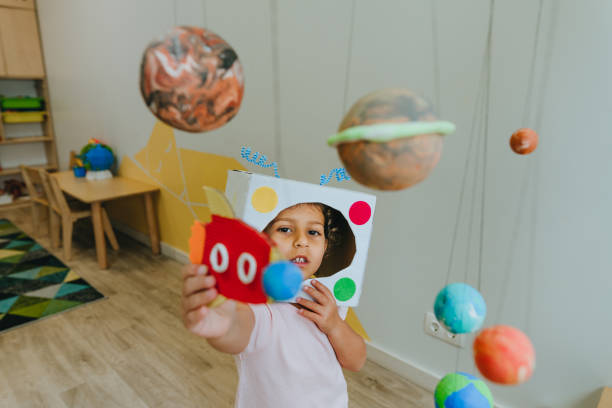 istock Little girl playing with paper spaceship learning Solar system planets 1413062605