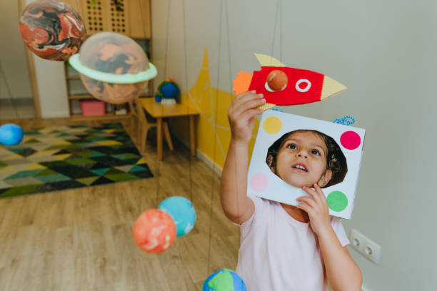 Little girl playing with paper spaceship learning Solar system planets