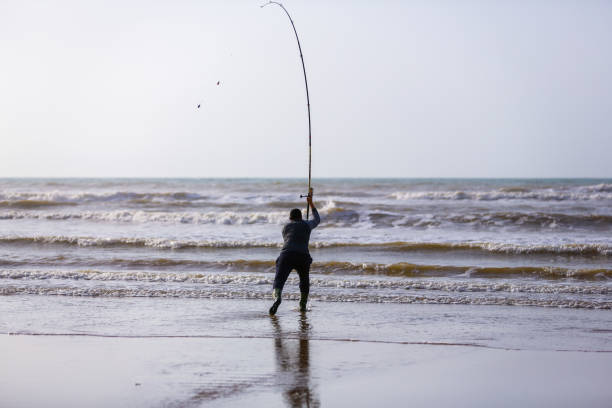 un pêcheur tenant son hameçon avec sa canne à pêche avec un magnifique coucher de soleil dans la ville de laâyoune - catch of fish photos photos et images de collection