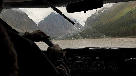 Looking through window of car to mountains of Aktru valley in Altai, Siberia, Russia. Beautiful summer nature landscape at during daytime with rain