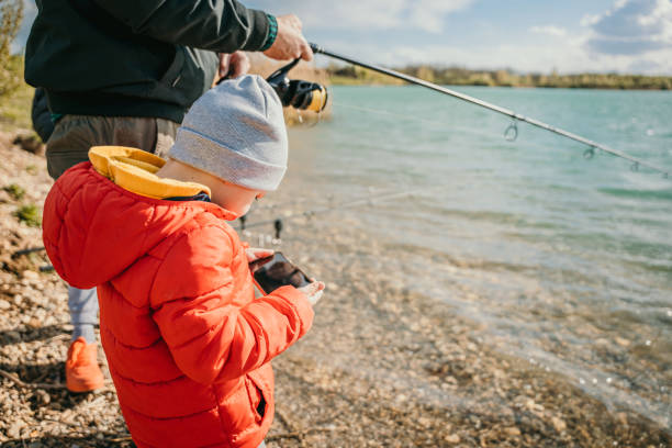 istock Man fishing on river with his son using mobile phone 1413067566