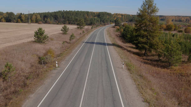 ウラルのカラフルな秋の森の間を移動する道路と車 - country road trucking car yellow ストックフォトと画像